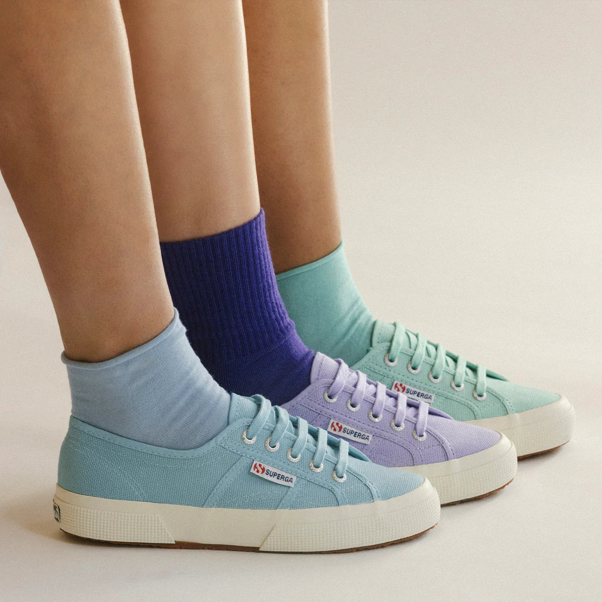 Three people wearing Superga 2750 Cotu Classic Sneakers in blue, purple, and green.